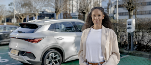 Frau steht vor einem E-Auto