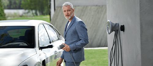 Mann lädt E-Auto